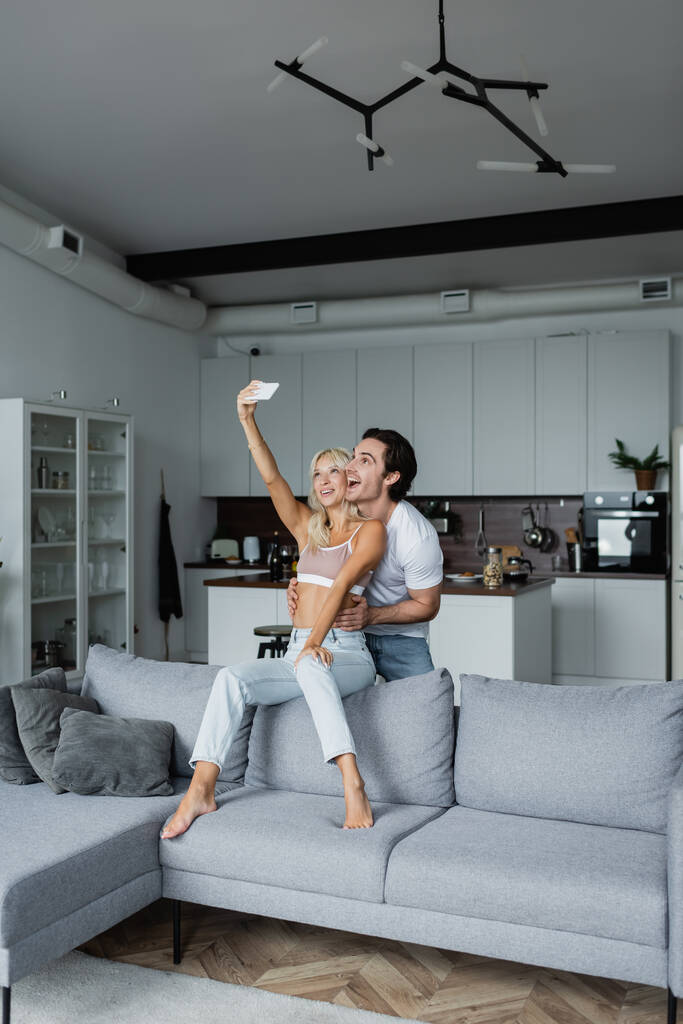 gelukkig vrouw het nemen van selfie met vriendje in woonkamer  - Foto, afbeelding