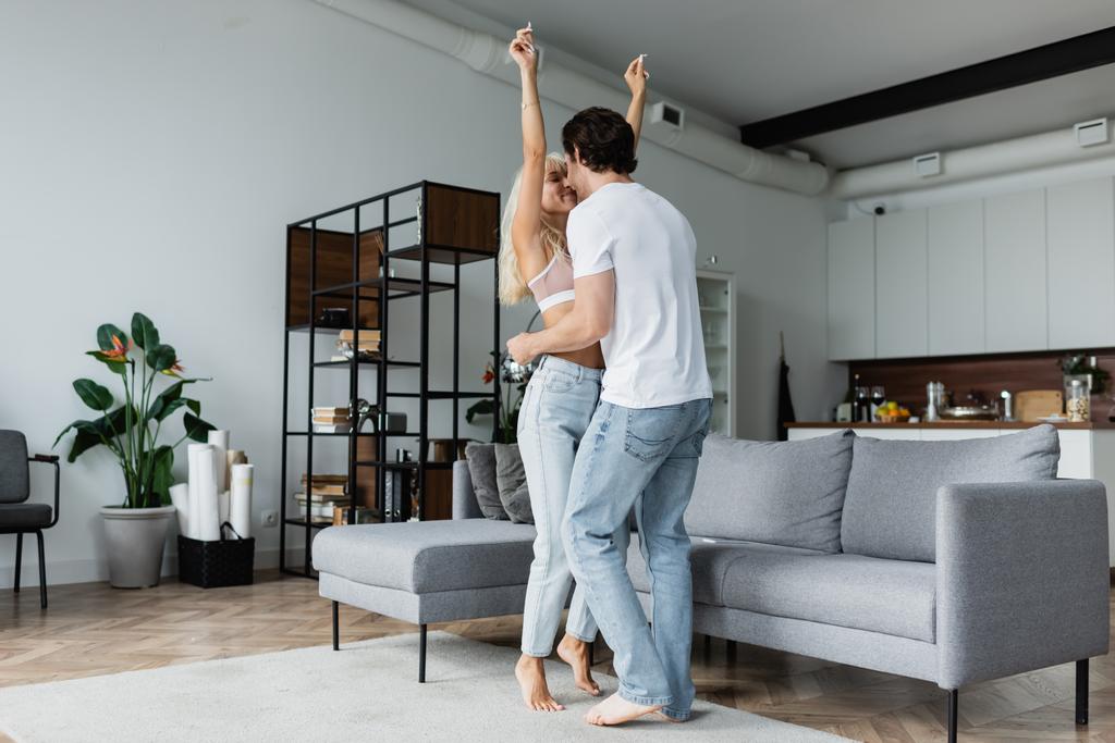 женщина поднимает руки, танцуя с парнем в гостиной  - Фото, изображение