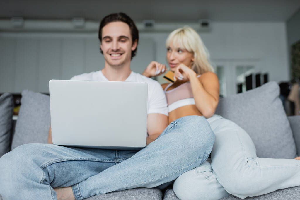couple flou et heureux avec carte de crédit et ordinateur portable faisant des achats en ligne  - Photo, image