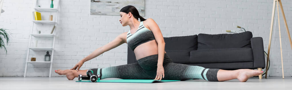 Spor kıyafetli hamile bir kadın yoga minderinde, pankartta poz veriyor. - Fotoğraf, Görsel