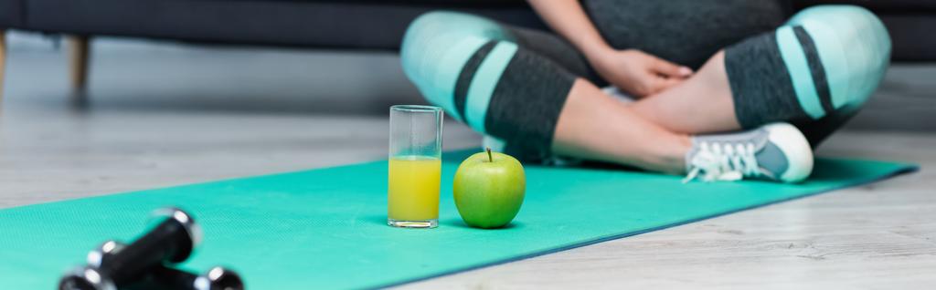 vista cortada de mulher grávida borrada meditando perto de suco de maçã e laranja, banner - Foto, Imagem