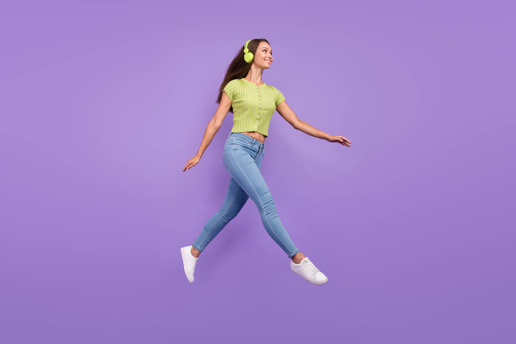 Vista completa del tamaño del cuerpo de una chica bastante alegre saltando escuchando melodía que se aísla sobre el fondo violeta violeta - Foto, Imagen