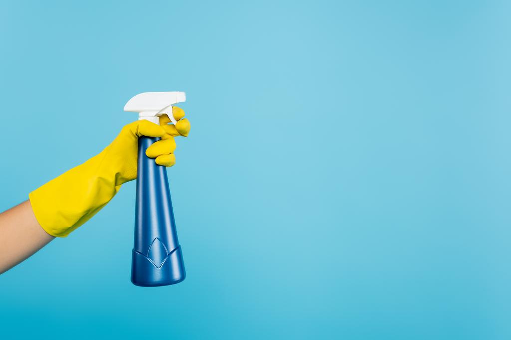 częściowy widok kobiety w żółtej gumowej rękawicy trzymającej butelkę spray z detergentem izolowanym na niebiesko - Zdjęcie, obraz