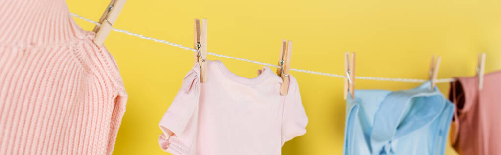 close up view of blurred clothes hanging on rope on yellow background, banner - Photo, Image