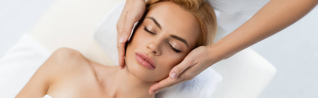 Sarışın müşteriye yüz masajı yapan masörün üst görüntüsü kapalı gözler, afiş - Fotoğraf, Görsel