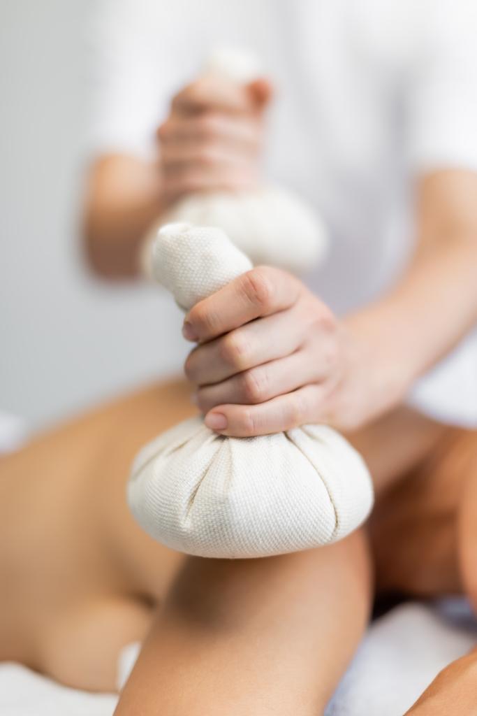 частковий вид масажиста, який тримає трав'яний мішок під час масажу клієнту
  - Фото, зображення