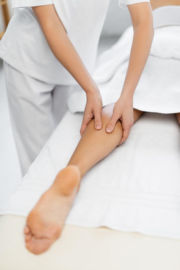 обрізаний вид масажиста робить масаж ніг розмитій жінці в спа-центрі
  - Фото, зображення