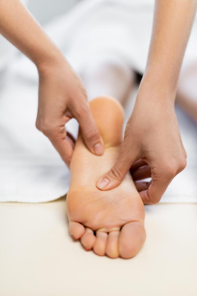 vista cortada de massagista fazendo massagem nos pés para o cliente  - Foto, Imagem
