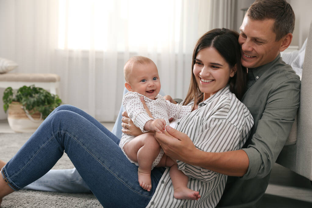 Happy family with their cute baby on floor in living room - Photo, Image