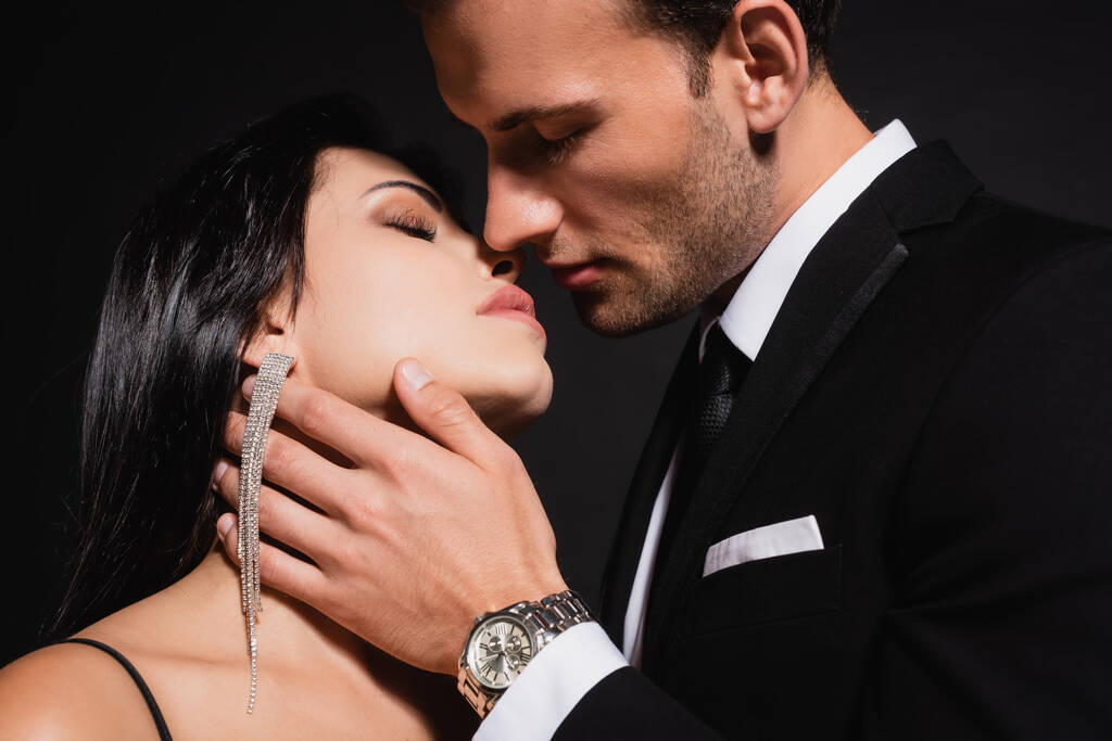 élégant homme baisers brunette femme isolé sur noir - Photo, image