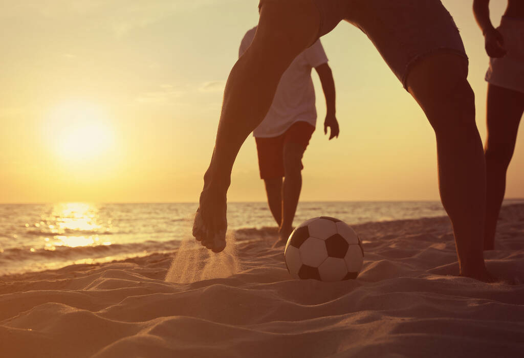 Přátelé hrají fotbal na pláži při západu slunce, detailní záběr - Fotografie, Obrázek