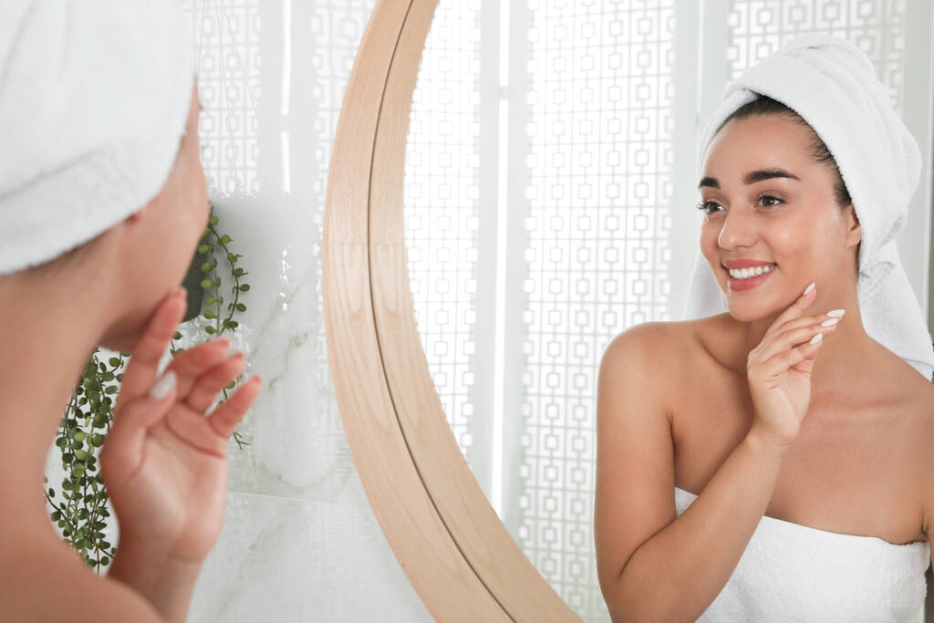 Красива молода жінка з ідеальною шкірою біля дзеркала у ванній кімнаті. Миття обличчя
 - Фото, зображення