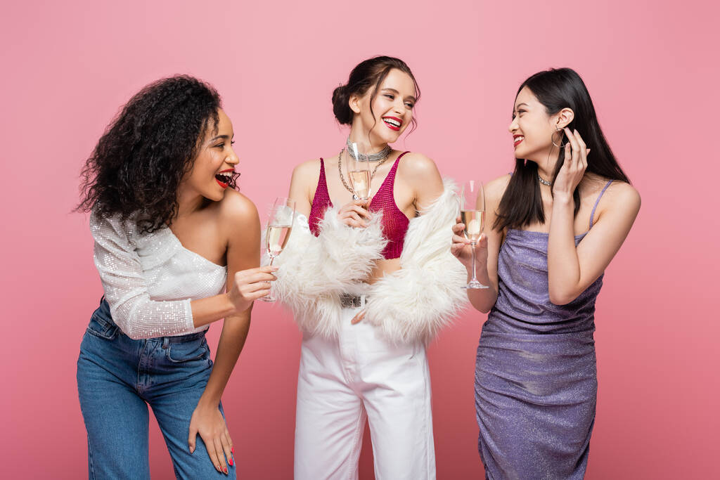 Lächelnde multiethnische Frauen mit Champagnergläsern auf rosa  - Foto, Bild