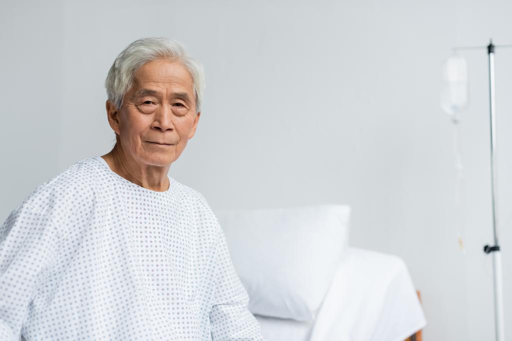 Senior asiático paciente mirando a cámara en hospital sala  - Foto, imagen