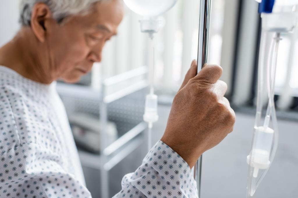 Rozmazané asijské pacient držení stojan s intravenózní terapií v nemocnici  - Fotografie, Obrázek