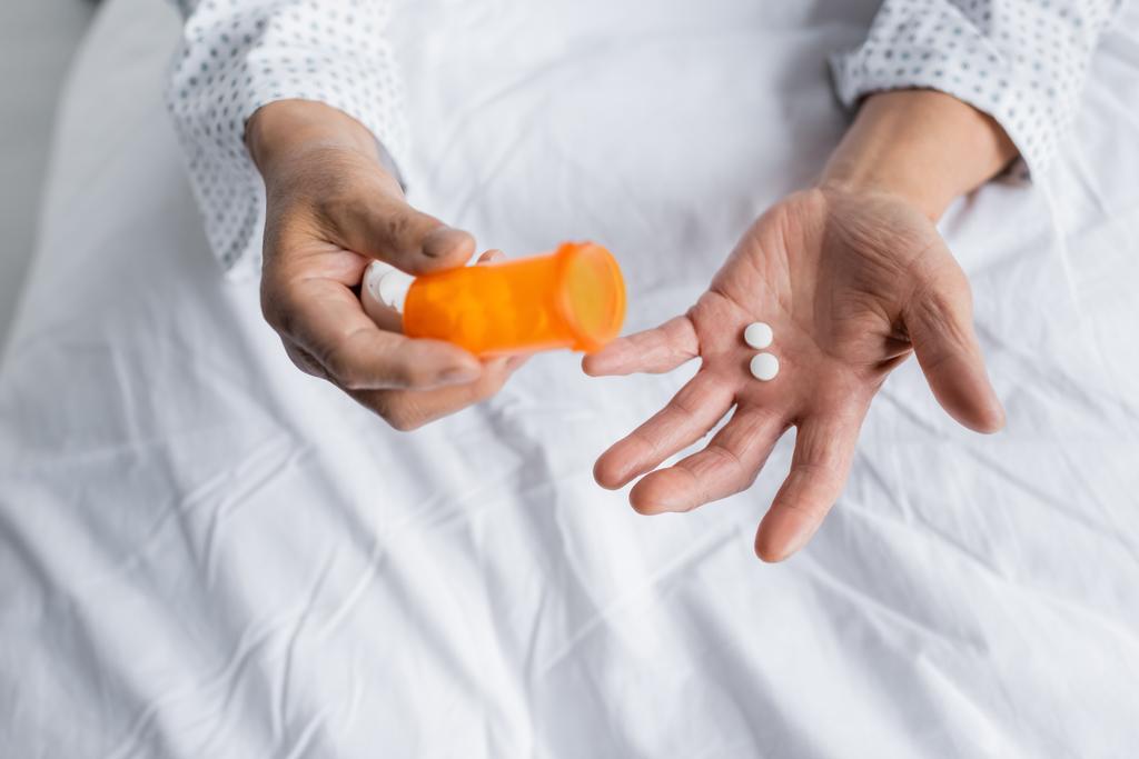 Vista cortada de pacientes idosos segurando pílulas na cama no hospital  - Foto, Imagem