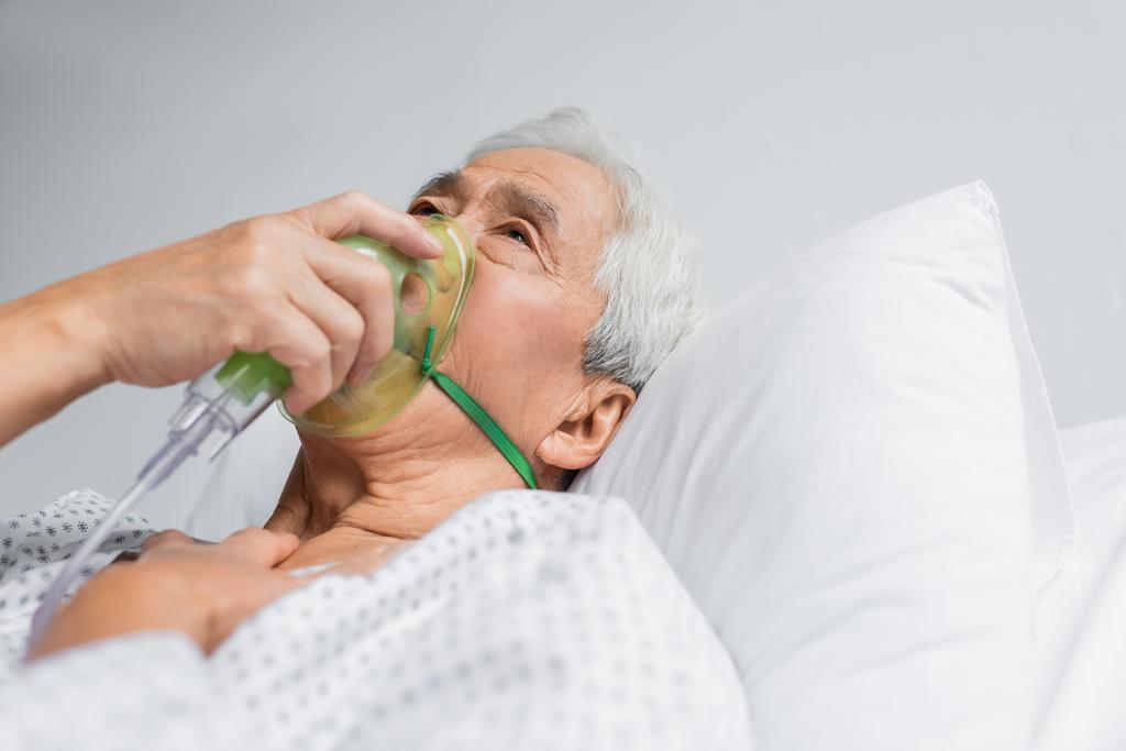 Yaşlı Asyalı hasta klinikte yatakta oksijen maskesi soluyor.  - Fotoğraf, Görsel