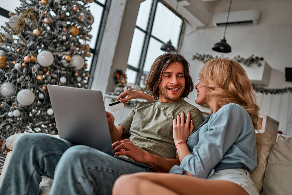 Muotokuva pari maksaa verkko-ostoksia luottokortilla kannettavalla. Joulun aika - Valokuva, kuva