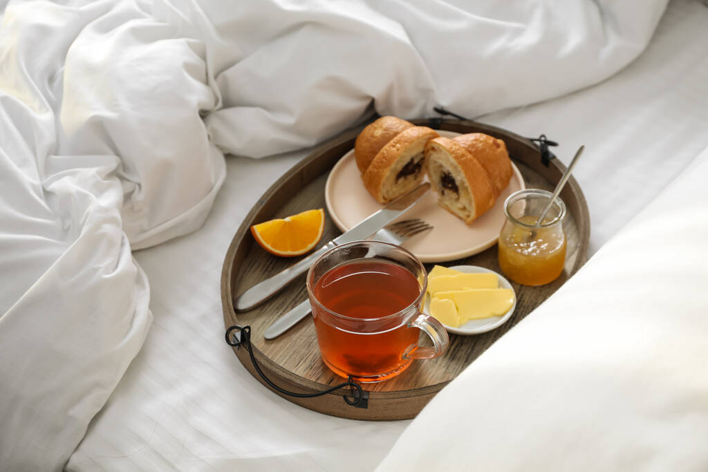 Tablett mit leckerem Frühstück morgens auf dem Bett - Foto, Bild