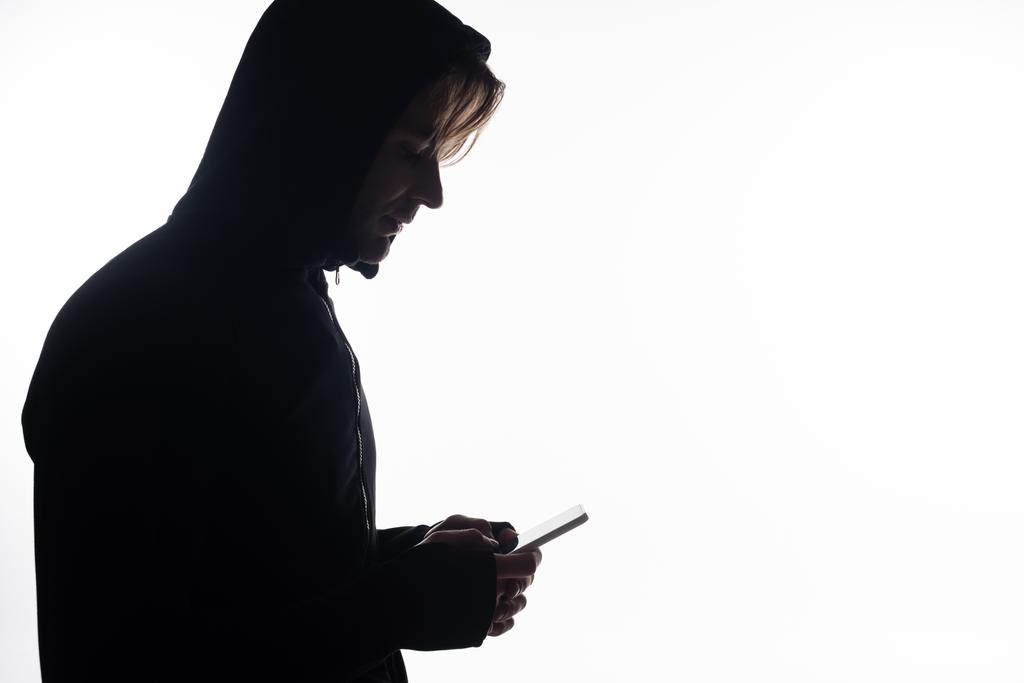 Widok z boku haker za pomocą smartfona izolowane na białym  - Zdjęcie, obraz