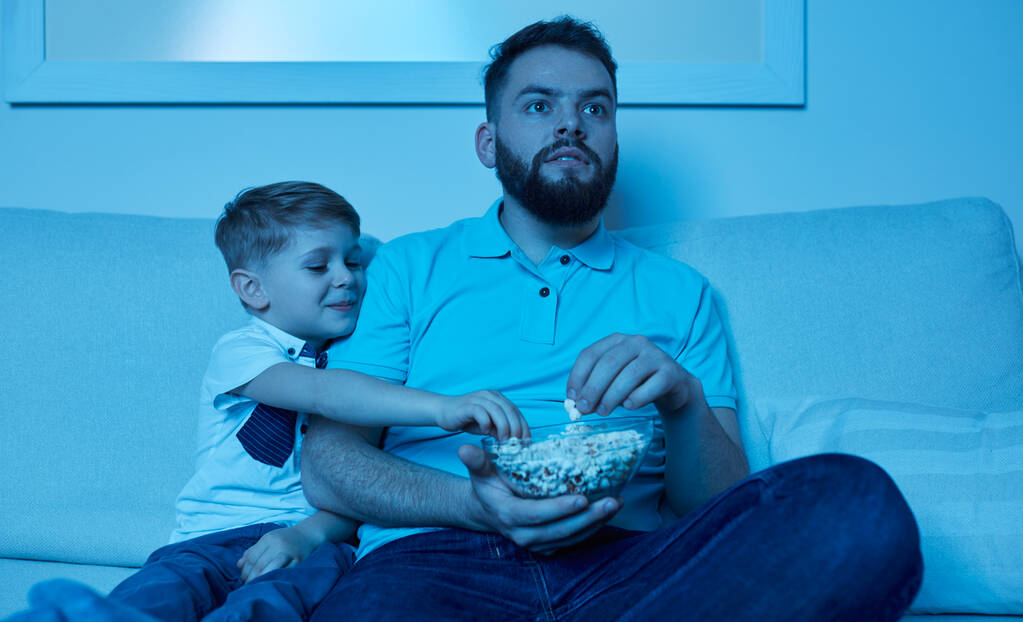 Мужчина и мальчик смотрят кино ночью - Фото, изображение