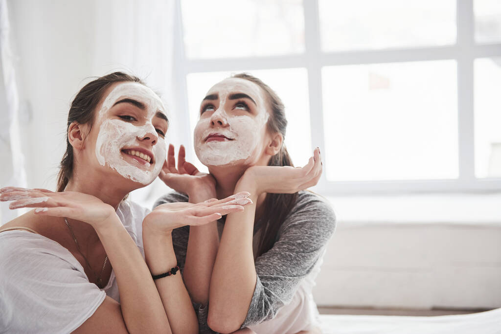 Gyönyörűek leszünk. Fogantatás a bőrápolás segítségével fehér maszk az arcon. Két nővére a hálószobában tölti a hétvégét.. - Fotó, kép