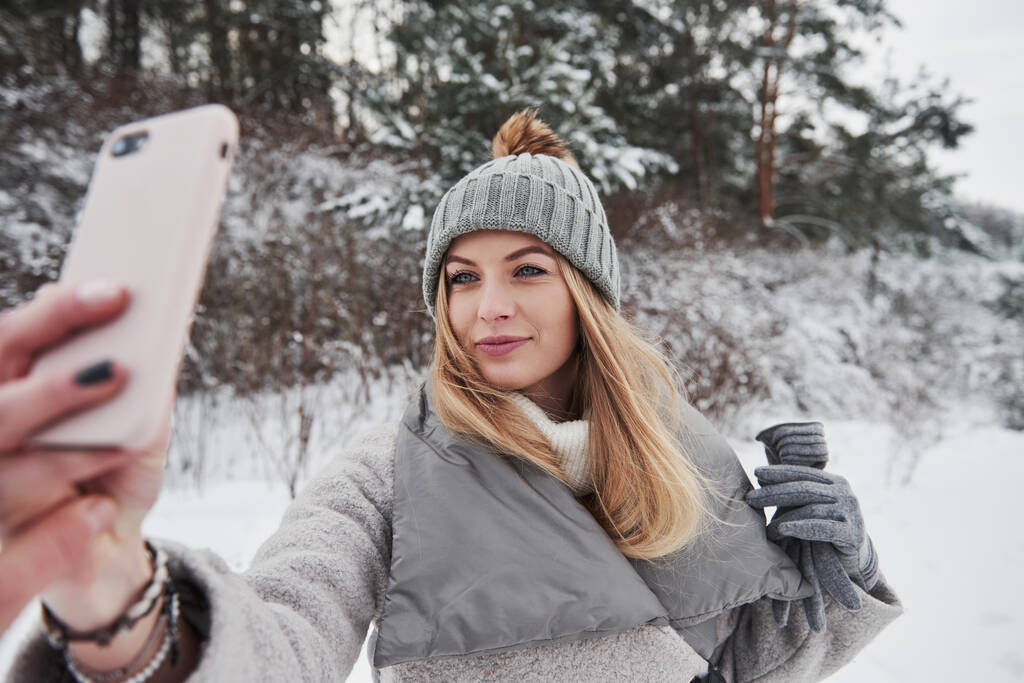 Karlı kış gününde ormanın yakınında selfie çeken bir kadın.. - Fotoğraf, Görsel