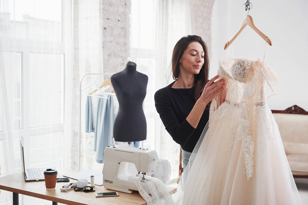 Mirando un vestido. Diseñadora de moda femenina trabaja en la ropa nueva en el taller. - Foto, Imagen