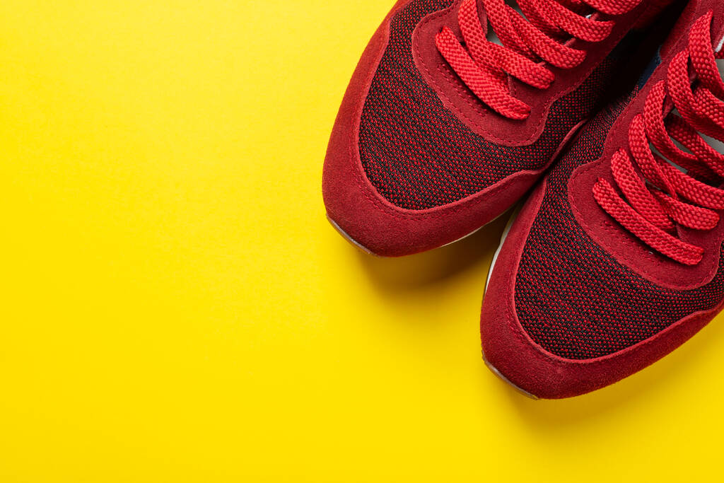 New red sneakers on a yellow background. space for text. Pair of sport shoes. - Photo, Image