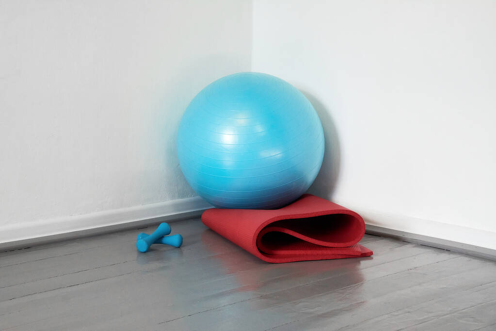 w rogu znajduje się niebieska piłka sportowa i czerwona mata do jogi. - Zdjęcie, obraz
