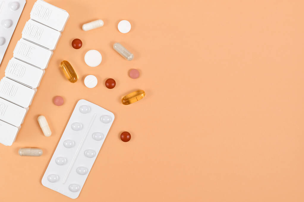 Medische pillen, capsules en pillen doos aan de zijkant van oranje achtergrond met kopieerruimte - Foto, afbeelding