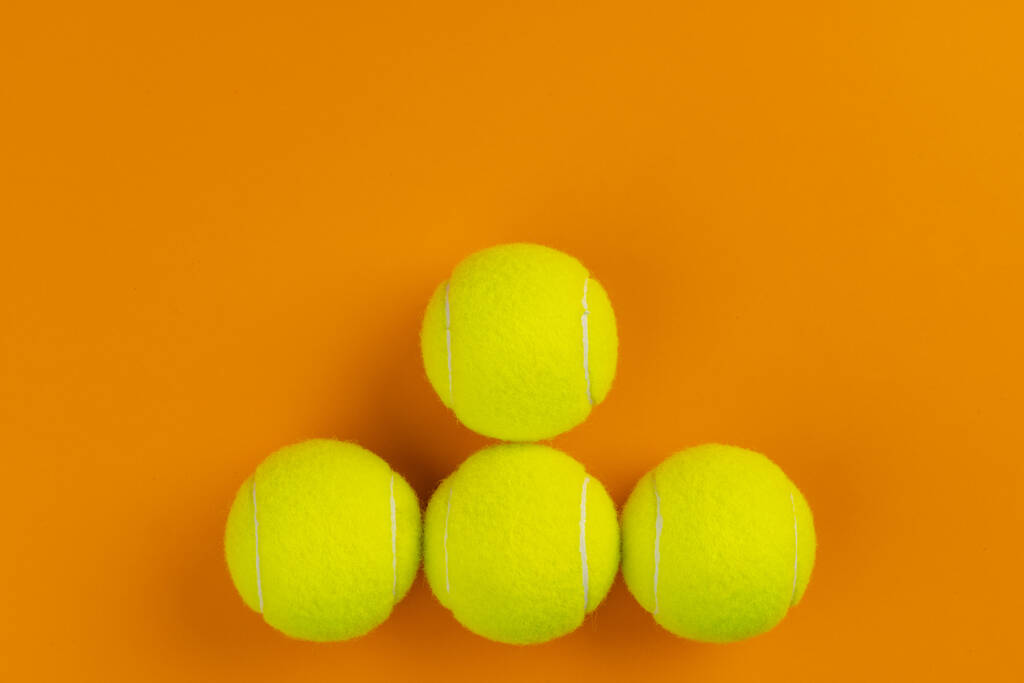Cuatro pelotas de tenis sobre fondo naranja - Foto, imagen
