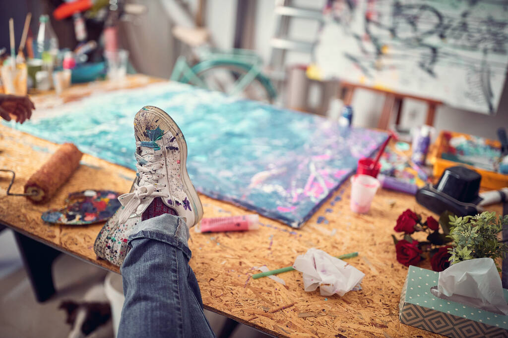 Веселе дозвілля.художник сидить і брудні ноги з різнокольоровою фарбою в студії
. - Фото, зображення