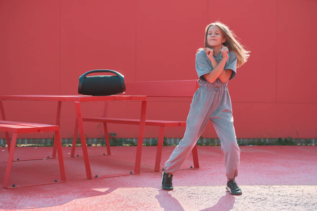 Cool teen girl taniec na zewnątrz słuchać muzyki z zewnątrz przenośny głośnik w słońcu. Ogłoszenie szkoły tańca - Zdjęcie, obraz