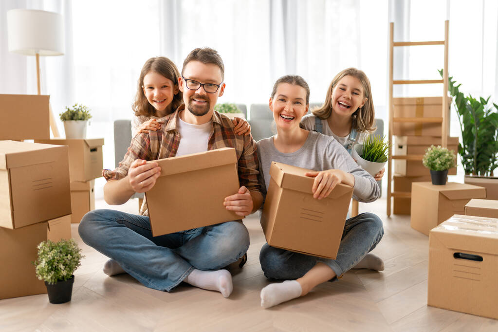 La giovane famiglia felice si trasferisce in un nuovo appartamento. Genitori e figlie con scatole. - Foto, immagini