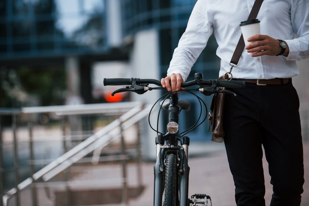 Een gezonde levensstijl. Zakenman in formele kleding met zwarte fiets is in de stad. - Foto, afbeelding