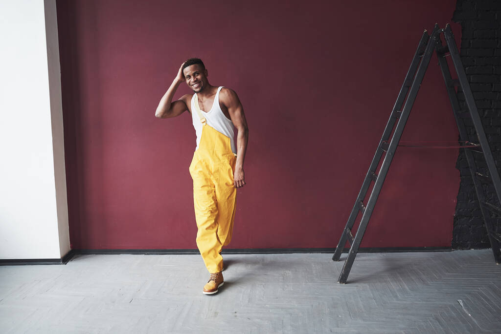 Űrszoba. A fiatal afro-amerikai munkásnak sárga egyenruhában van valami munkája.. - Fotó, kép