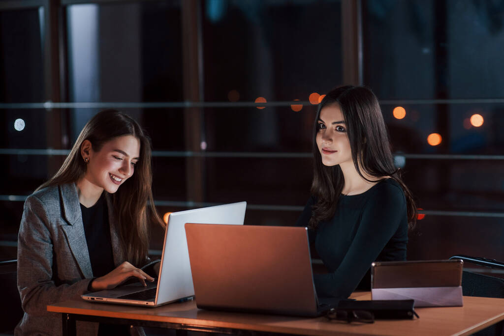 Girl looks straight forward in front of she. Team of young business people works on their project at night time in the office. - Foto, Imagem