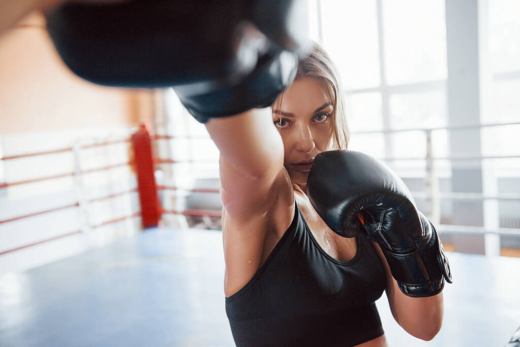 Nunca te rindas. Mujer deportista entrenando en el ring de boxeo. En ropa de color negro. - Foto, imagen