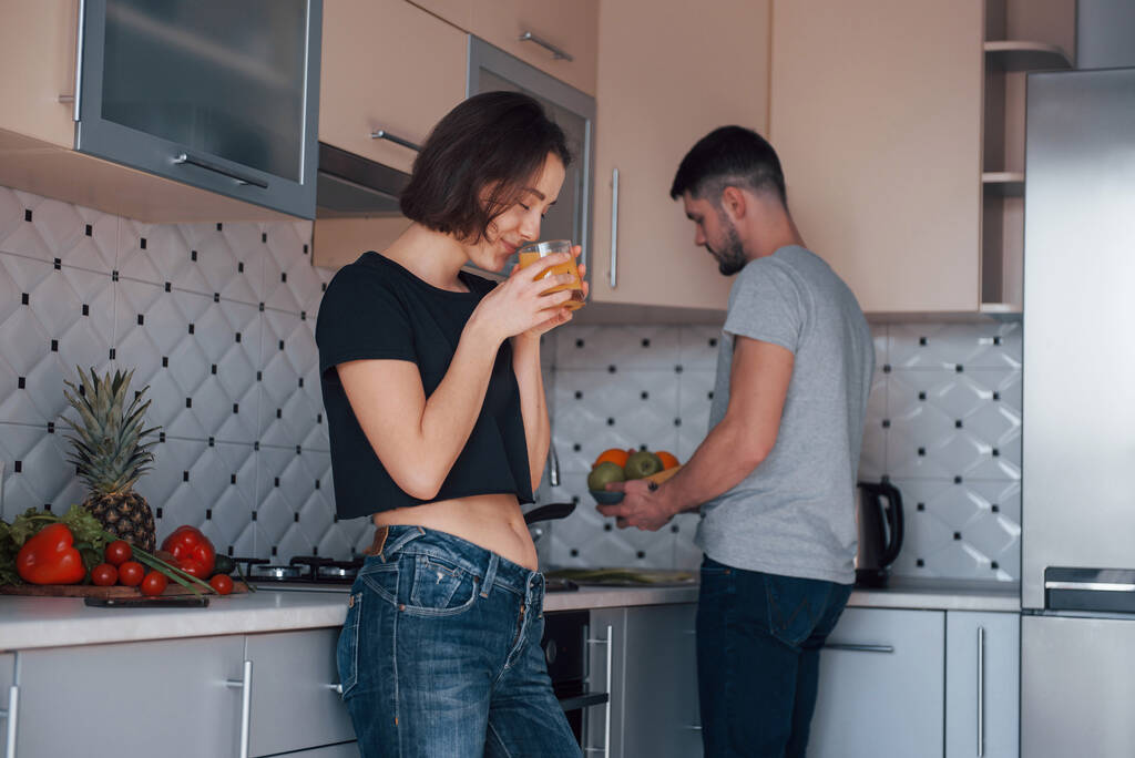 Tasting fresh drink. Young couple in the modern kitchen at home at their weekend time in the morning. - Photo, Image