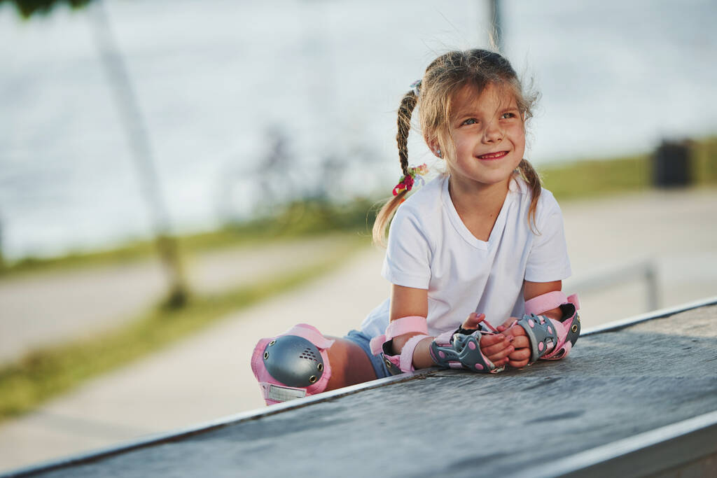 Açık havada patenli şirin küçük bir kız ekstrem sporlar için rampada oturuyor.. - Fotoğraf, Görsel