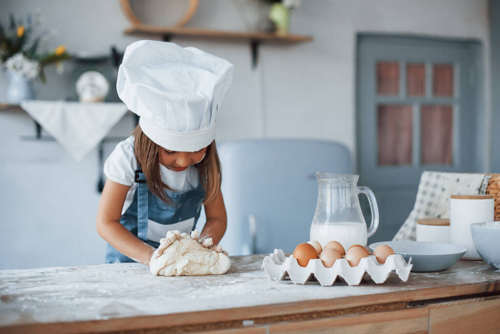 Χαριτωμένο παιδί σε λευκό στολή σεφ προετοιμασία των τροφίμων στην κουζίνα. - Φωτογραφία, εικόνα
