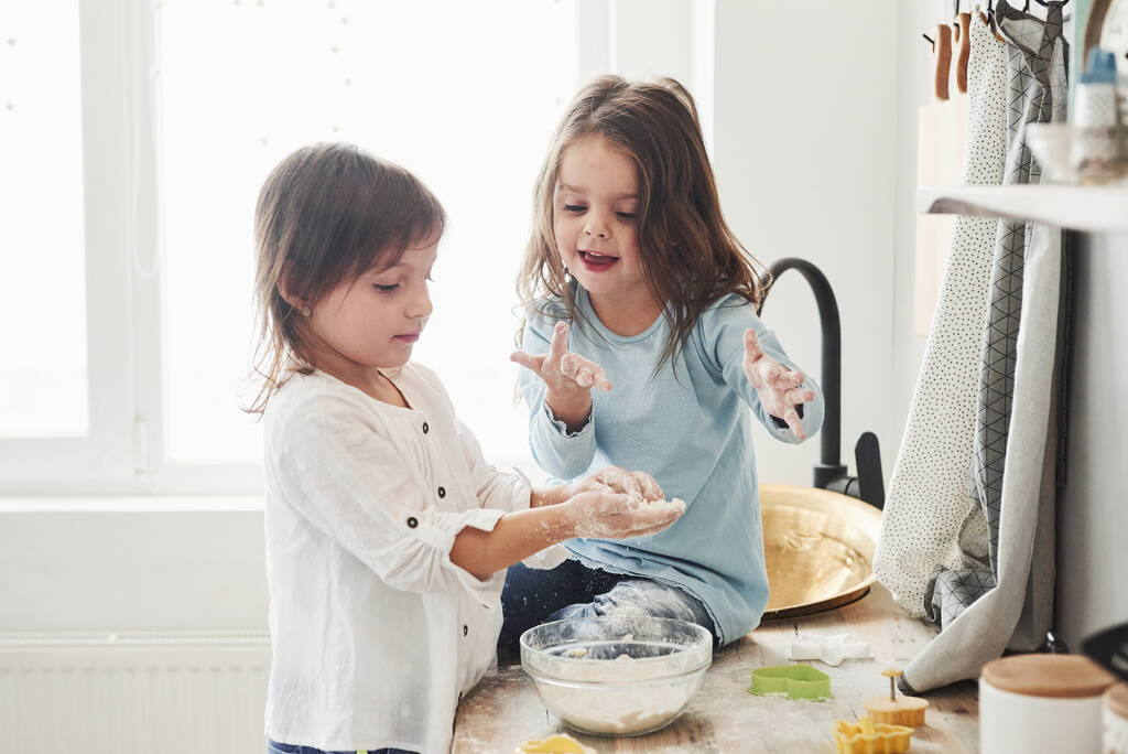 Gyerekjátékok. Óvodás barátok megtanulják, hogyan kell főzni liszttel a fehér konyhában. - Fotó, kép