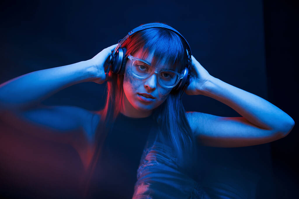Kunst van cyberpunk. Studio opgenomen in donkere studio met neon licht. Portret van een jong meisje. - Foto, afbeelding