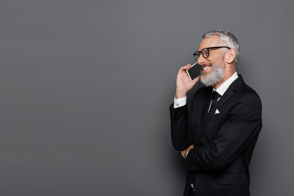 veselý podnikatel středního věku mluví na mobilu na šedé - Fotografie, Obrázek
