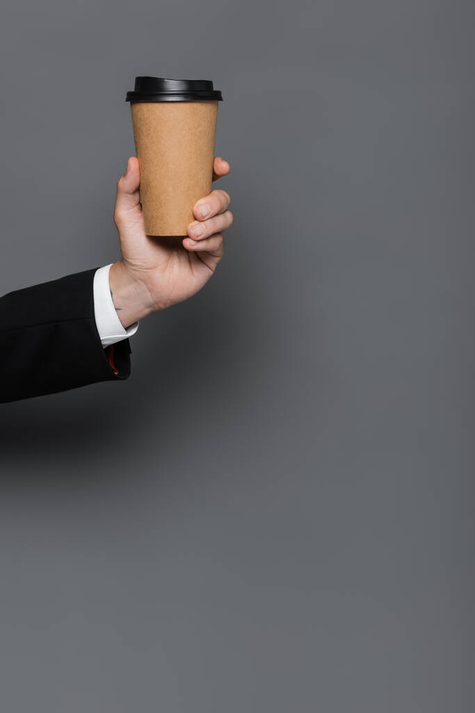 vista recortada del hombre de negocios sosteniendo taza de papel en gris - Foto, Imagen