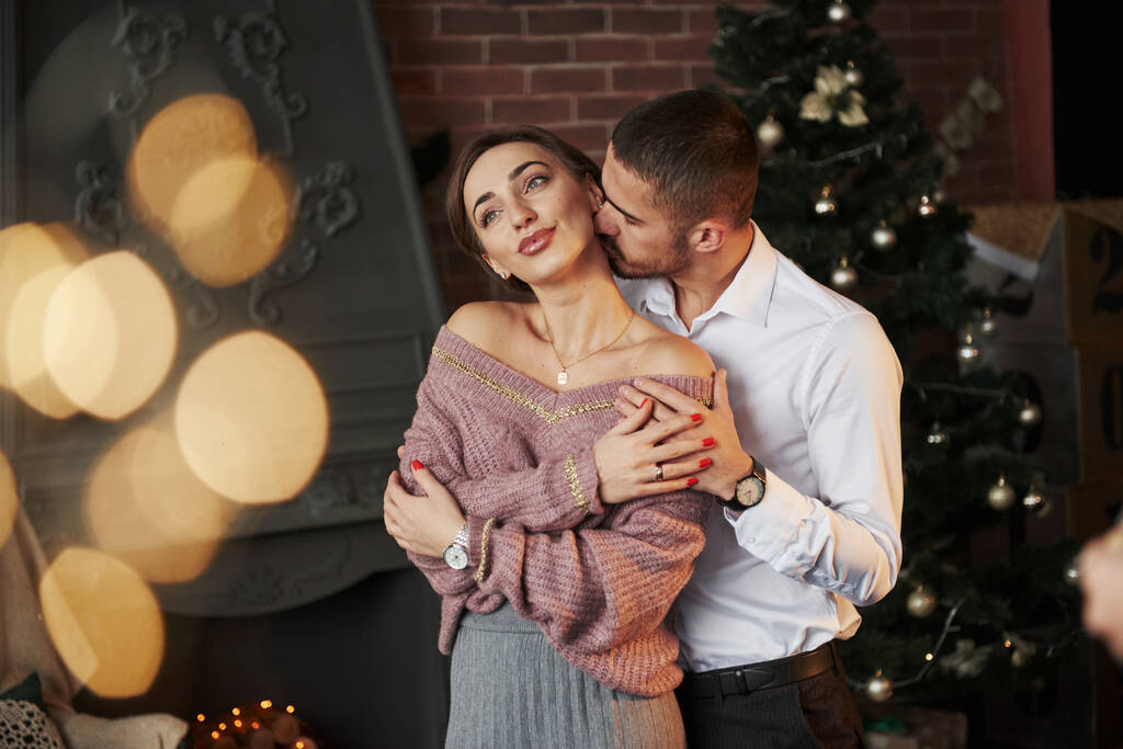 Retrato romántico de gente hermosa. Bonita pareja celebrando el año nuevo frente al árbol de Navidad. - Foto, imagen