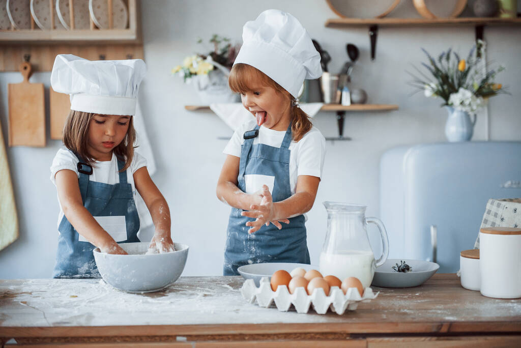 Familienkinder in weißer Koch-Uniform bereiten Essen in der Küche zu. - Foto, Bild