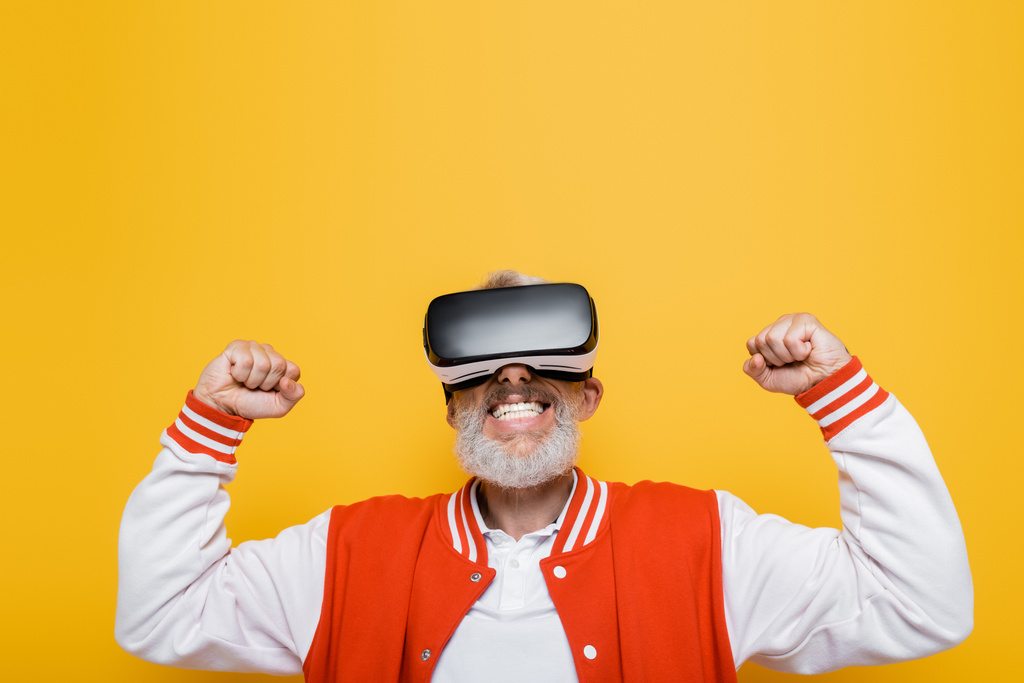 middle aged man in bomber jacket and vr headset rejoicing isolated on yellow - Photo, Image