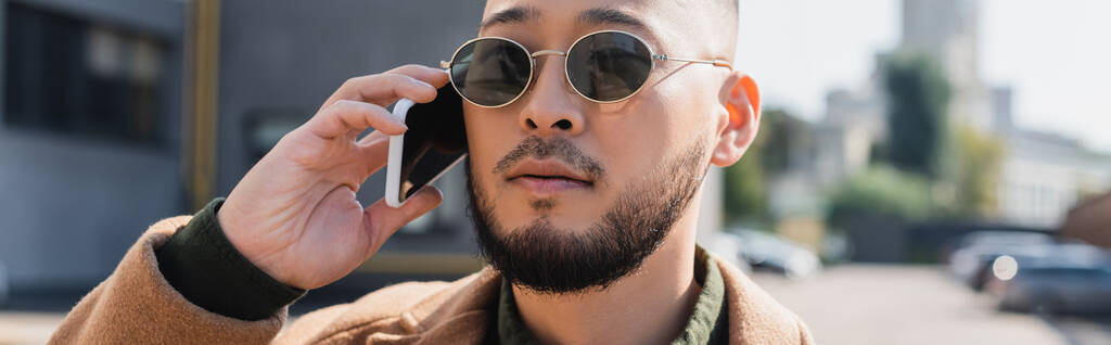 asiatico uomo in elegante occhiali da sole parlando su smartphone all'aperto, banner - Foto, immagini